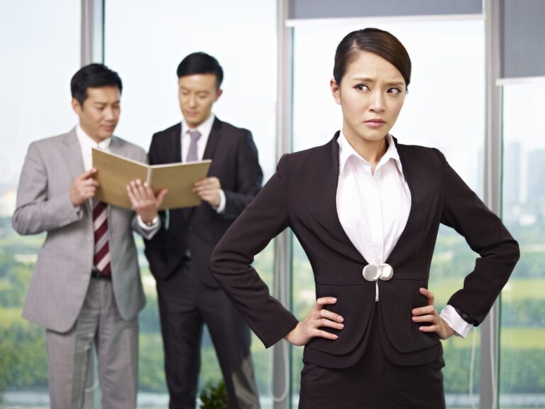 Portrait,Of,An,Unhappy,Young,Asian,Businesswoman,With,Her,Colleagues
